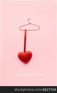 Creative valentines concept photo of a heart on a hanger on pink background.