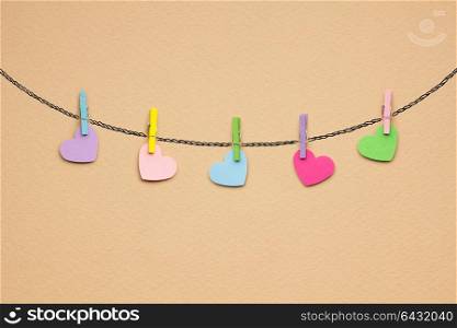 Creative valentines concept photo of hearts pinned on the rope on brown background.