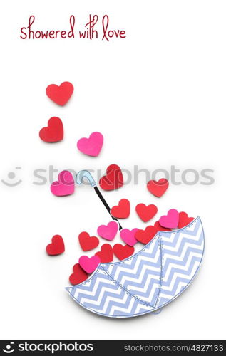 Creative valentines concept photo of paper umbrella with hearts raining down on white background.