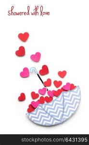 Creative valentines concept photo of paper umbrella with hearts raining down on white background.