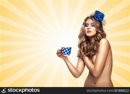 Creative vintage photo of a beautiful naked pin-up girl in a hat, drinking tea or coffee from a polka dot cup on colorful abstract cartoon style background.