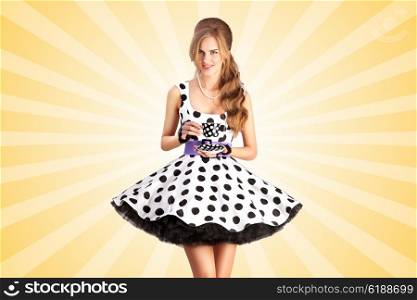 Creative vintage photo of a beautiful pin-up girl in a polka dot dress, holding a cup of tea on colorful abstract cartoon style background.