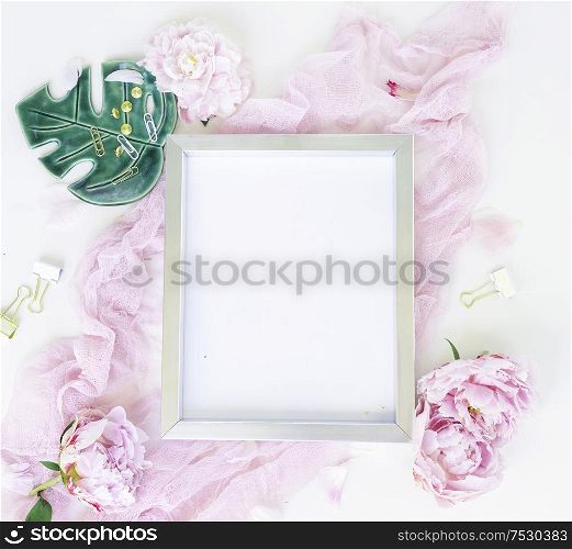 Creative wedding composition with metalic photo frame mock up, pink blanket, flowers on white desk background. Flat lay, top view stylish art concept.. Creative wedding composition