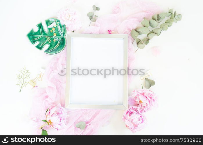 Creative wedding composition with metalic photo frame mock up, pink blanket, flowers on white desk background. Flat lay, top view stylish art concept.. Creative wedding composition