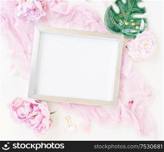 Creative wedding composition with metalic photo frame mock up, pink blanket, flowers on white background. Flat lay, top view stylish art concept.. Creative wedding composition
