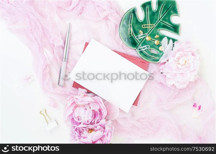 Creative wedding composition with wedding invitation mock up, pink blanket, flowers, eucalyptus branches and brushes on white background. Flat lay stylish art concept with copy space on white card.. Creative wedding composition