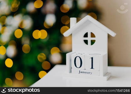 Creative white house with written date against New Year background, tree with lights. First of January. Happy New Year concept