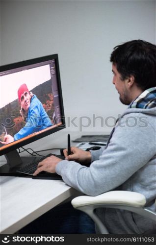 creative worker, photo editor working on graphic tablet at his desktop computer at small startup office