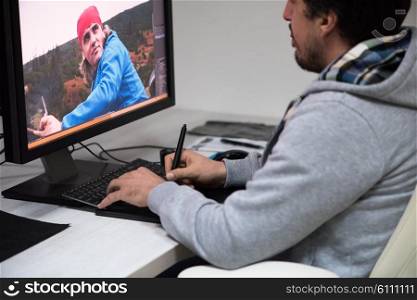 creative worker, photo editor working on graphic tablet at his desktop computer at small startup office