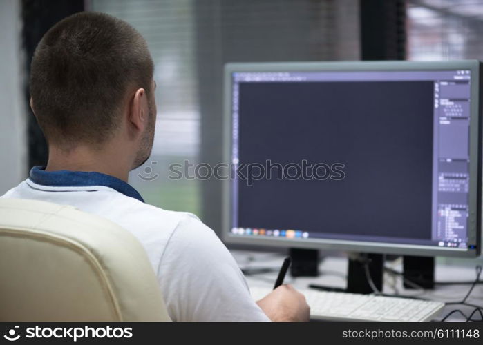 creative worker, photo editor working on graphic tablet at his desktop computer at small startup office