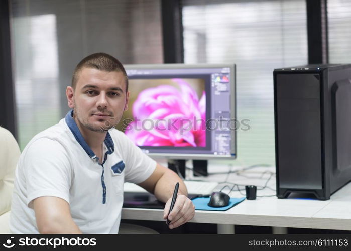 creative worker, photo editor working on graphic tablet at his desktop computer at small startup office