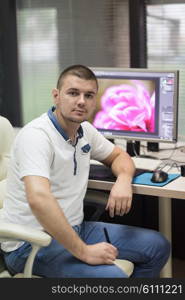 creative worker, photo editor working on graphic tablet at his desktop computer at small startup office