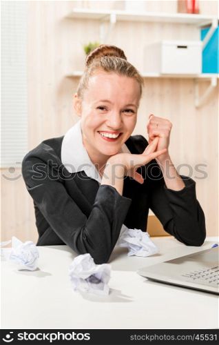 creative worker smiling in office, and crumpled paper on the desk