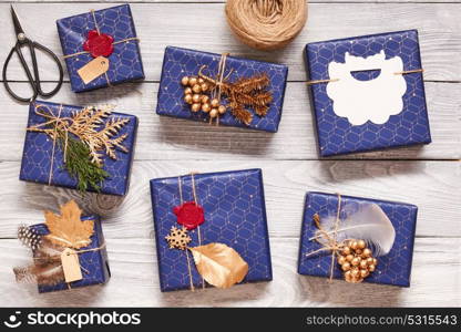 Creatively wrapped and decorated christmas presents in boxes on white wooden background.Top view from above.