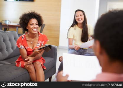 Creatives Having Informal Meeting On Sofas In Design Studio