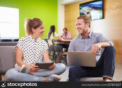 Creatives Having Informal Meeting On Sofas In Design Studio