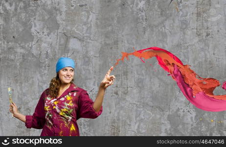 Creativity and art. Young woman painter with brush and colorful splashes above