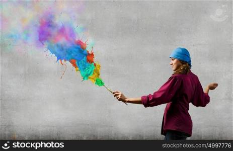 Creativity and art. Young woman painter with brush and colorful splashes above