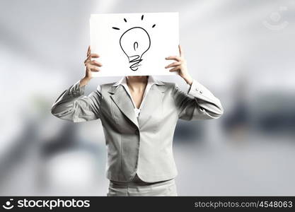 Creativity concept. Businesswoman hiding her face behind paper with drawing