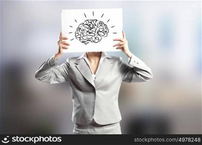 Creativity concept. Businesswoman hiding her face behind paper with drawing