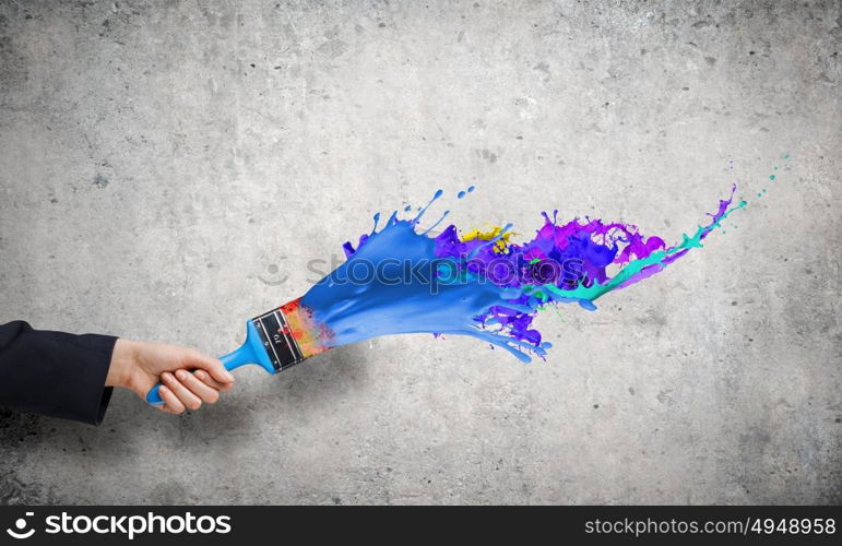 Creativity concept. Close up of business person hand holding paint brush