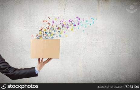 Creativity concept. Close up of hand holding carton box with colorful letters