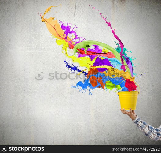 Creativity concept. Close up of hand splashing colorful paint from colorful bucket