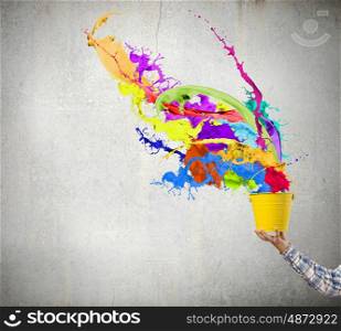 Creativity concept. Close up of hand splashing colorful paint from colorful bucket