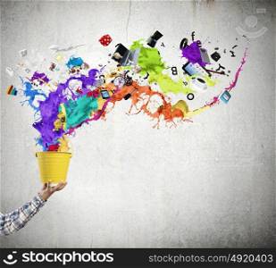 Creativity concept. Close up of hand splashing colorful paint from colorful bucket
