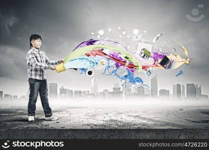 Creativity concept. Cute boy splashing colorful paint from bucket