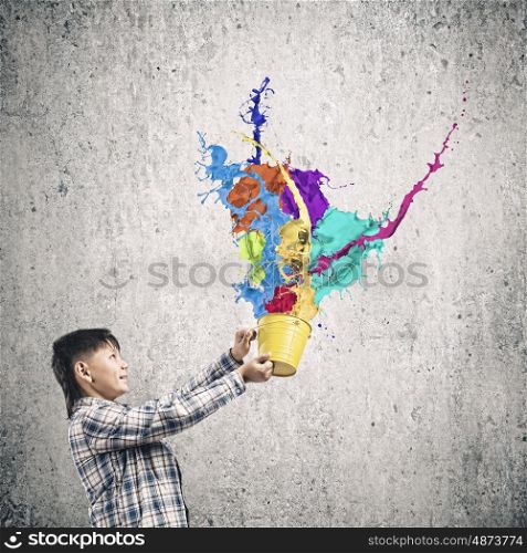 Creativity concept. Cute boy splashing colorful paint from bucket