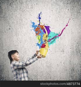 Creativity concept. Cute boy splashing colorful paint from bucket