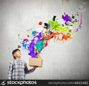 Creativity concept. Cute boy splashing colorful paint from carton box