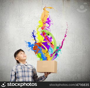 Creativity concept. Cute boy splashing colorful paint from carton box