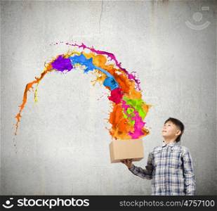 Creativity concept. Cute boy splashing colorful paint from carton box