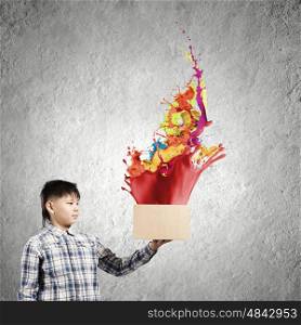 Creativity concept. Cute boy splashing colorful paint from carton box