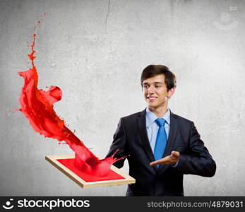 Creativity concept. Handsome businessman holding frame with colorful splashes