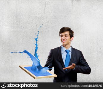 Creativity concept. Handsome businessman holding frame with colorful splashes