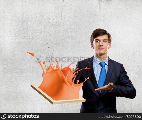 Creativity concept. Handsome businessman holding frame with colorful splashes