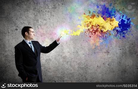 Creativity concept. Young businessman in suit and colorful splashes