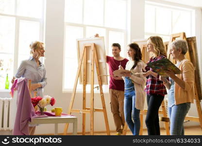 creativity, education and people concept - drawing teacher showing still life composition to group of artists or students at art school studio. drawing teacher and students at art school