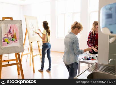 creativity, education and people concept - group of woman artists or students with colors painting still life pictures on easels at art school studio. woman artists with colors painting at art school