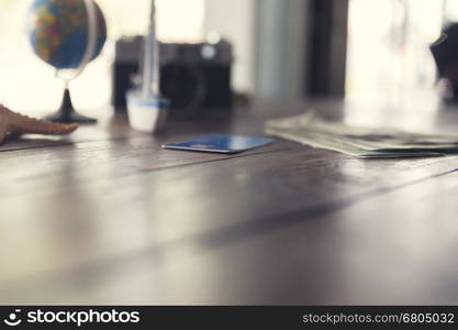 credit card, banknote money, globe, camera, ship and starfish figurine on wooden table for use as traveling concept (vintage tone and selected focus)