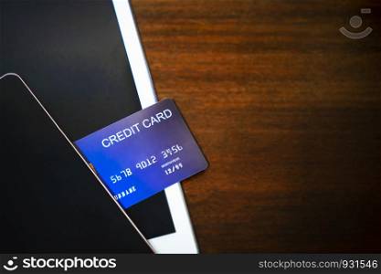Credit card with mobile and tablet on wood table with free space for text. Business and technology concept.