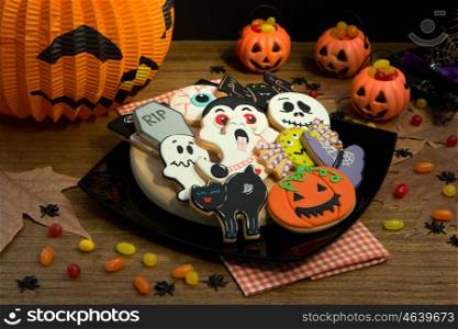 Creepy Halloween cookies and pumpkin baskets filled with candies on a wooden table