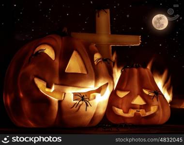 Creepy Halloween night, glowing carved pumpkin with scary horrible spiders, cross and burning flame on the graveyard in full moon night