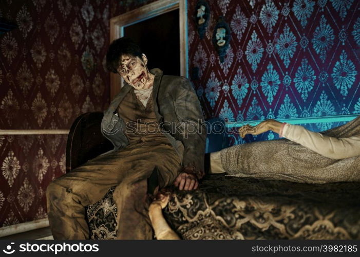 Creepy scary zombie on bed looking at camera. Halloween horror film. Post apocalyptic concept. Zombie sitting on bed looking at camera