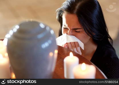 cremation, people and mourning concept - woman with wipe and cinerary urn crying at funeral in church. woman with cremation urn at funeral in church