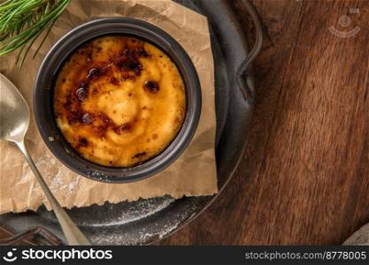 Creme brulee. Bowls with French vanilla cream dessert with caramelised sugar on top, spoons, dark rustic table. Leite creme, portuguese desert similar to creme brulee, cream brulee and burnt cream.