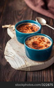 Creme brulee in the pots on the wooden board